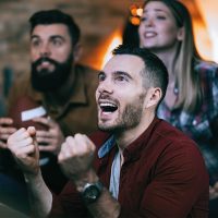 young-man-cheering-his-team-while-watching-sports-championship-with-friends